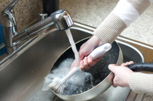 Person washing a pan with natural castile soap at a kitchen sink