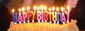 Colorful birthday candles spelling "HAPPY BIRTHDAY" lit atop a cake, celebrating a special occasion.