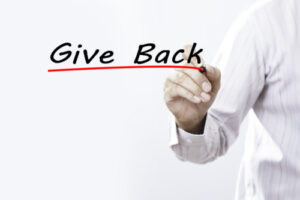 Hand writing the words “Give Back” with red underline, symbolizing community support and charitable giving
