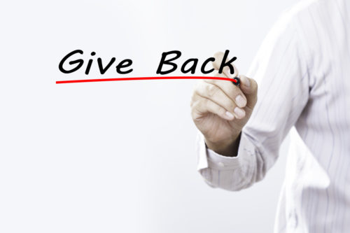 Hand writing the words “Give Back” with red underline, symbolizing community support and charitable giving
