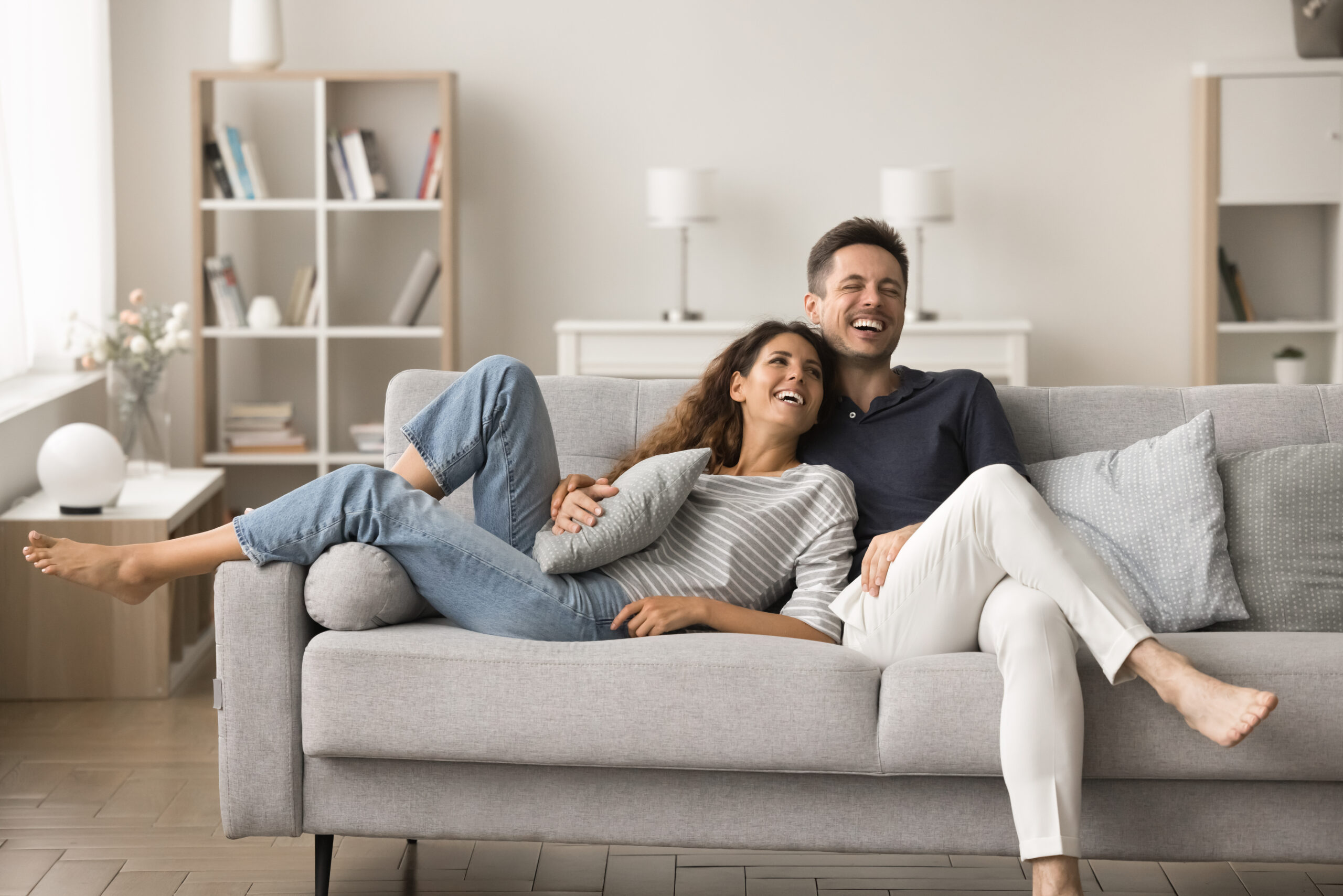 Happy couple relaxing together on a sofa in a clean bright living room after Enovana Green Cleaning's eco-friendly house cleaning service in Raleigh NC