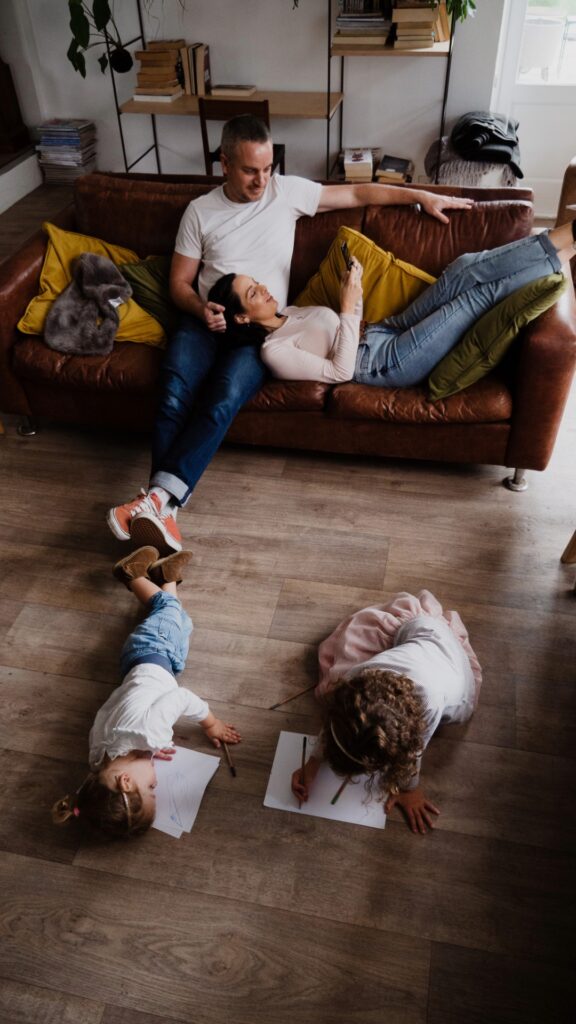 Family relaxing at home with children drawing on the floor, reflecting the safety of Enovana's non-toxic cleaning products for kids
